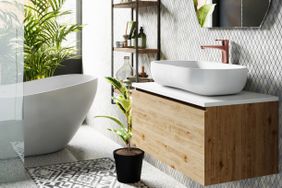 Corner of hotel bathroom with grey tiled walls, round mirror, white bath and large window. 3d rendering