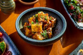 Bowl of tofu, seasoned with black and white sesame seeds and chopped scallion