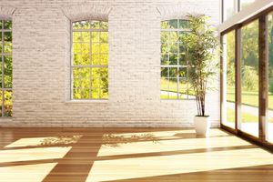 home interior with light hardwood floors, white brick wall, and a potted plant, with natural light coming in through sliding doors