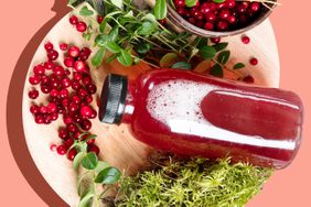 cranberry juice in a bottle on a plate surrounded by cranberries