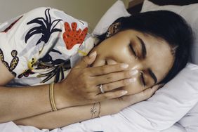 A young Asian woman on the bed feels sleepy, she is lying on the side and yawning