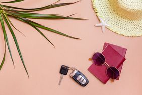 Summer bright travel flat lay with sunglasses, passports, car keys and a straw hat on a beige background