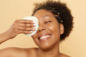 Beautiful young black woman with removal disk on beige background. Eco-friendly