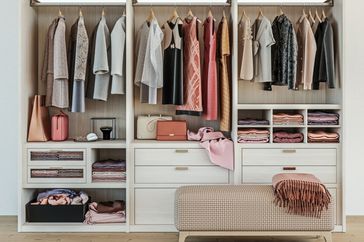 modern wooden wardrobe with women clothes hanging on rail in walk in closet design interior