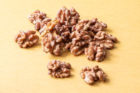 Shelled walnut halves on a beige or yellow background