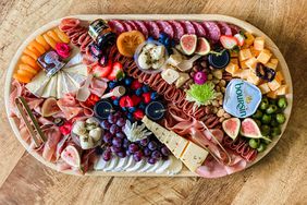 charcuterie board by French Boards and Bites NY with meats, cheese, olives, grapes, and berries.