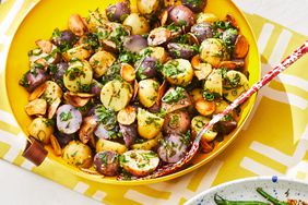 Garlic Herb Potato Salad in a yellow bowl with red speckled serving spoon.