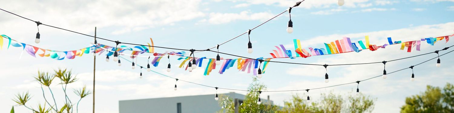 Outdoor gathering with string lights and a colorful banner