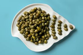 capers in a shell shaped dish on a blue background