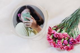 flowers next to a mirror with reflection of a person taking a selfie