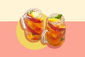 Two glass mugs filled with iced tea, infused with fruit slices, against a pink background