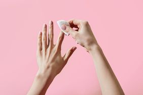 A woman's hands removing nail polish