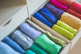 A lot of colorful clothes are neatly arranged in a wardrobe drawer. The concept of storage and order. Organization of space.