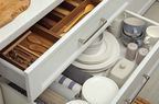 Open drawers of kitchen cabinet with different dishware