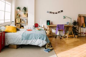 Cozy interior gen z teenager room with bed, workplace, digital devices, plants, photos and some clothes. Home interior room