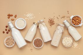 Dairy free alternative plant and nut milk in glass bottles on a gray background.