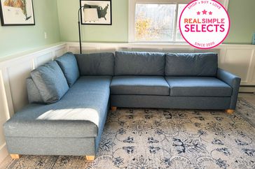 Blue sectional sofa set up on rug in room with green walls