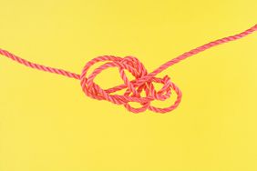 pink string tangled in a knot on a yellow background