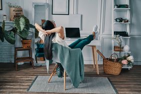 Rear view of young woman keeping hands behind head while sitting in home office