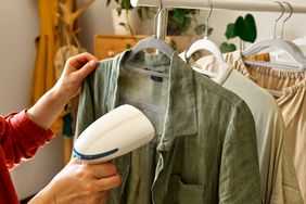 Unrecognizable woman steaming washed clothes at home. Housewife daily routine. Housekeeping concept.