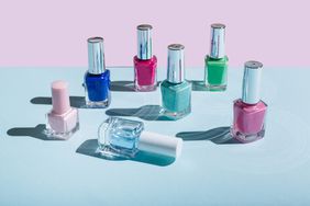 Bottles of colorful nail polish on pastel blue and pink background. Manicure and pedicure concept. Flat lay, top view.