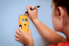 Woman using a stud finder on a wall