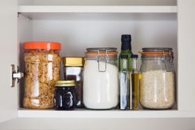 stocked kitchen pantry with food - jars and containers of cereals, jam, coffee, sugar, flour, oil, vinegar, rice